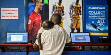A man with his child bets on football games at sports betting shop in Uganda. AFP PHOTO